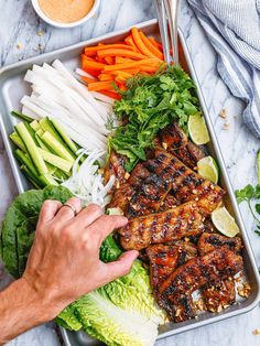 a tray with chicken, lettuce, carrots and other vegetables on it