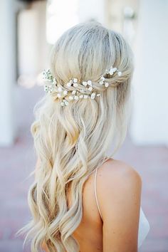 a woman with long blonde hair and flowers in her hair is wearing a white dress