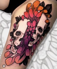 a woman's thigh with two skulls and flowers on the thighs, both decorated in black and orange