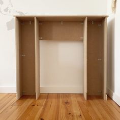 an empty room with wooden flooring and white paint on the walls, including two open shelves