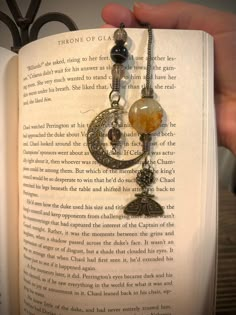 a person holding an open book with charms on it's pages and reading the book