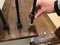 a person is holding two pieces of metal on a wooden table