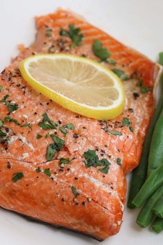 a piece of salmon and green beans on a white plate