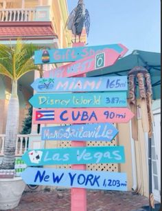 a street sign with many different colored signs on it's post in front of a building