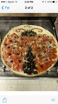 a pizza sitting on top of a metal rack next to an oven with pepperoni and olives