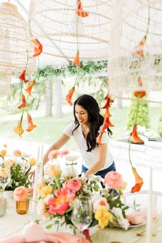 a woman setting a table with flowers on it