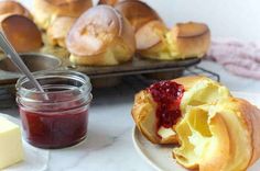 bread rolls with jam and butter on a plate next to other baked goods, including butter