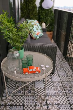 a small table with two glasses and a toy car on it sitting on a tiled patio