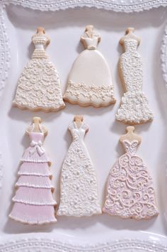 decorated cookies in the shape of dresses on a white plate with lace trimmings