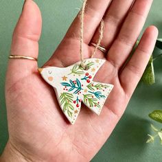 a hand holding a ceramic ornament in the shape of a christmas tree decoration