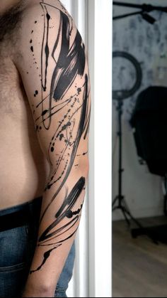 a man's arm with black ink on it in front of a chair and wall