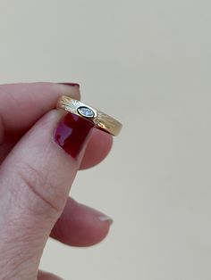 a woman's hand holding a gold ring with two blue stones on the side