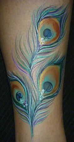 an artistic tattoo design on the leg of a woman's legs with peacock feathers