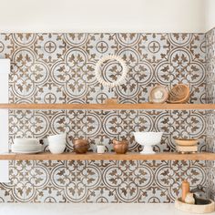 a shelf with bowls and plates on it next to a wallpapered wall in a kitchen