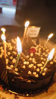 a chocolate birthday cake with lit candles on it