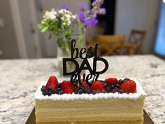 a piece of cake with berries on top and the words best dad spelled in black