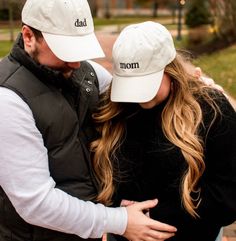 a man and woman hugging each other while wearing hats