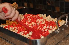 a person scooping something out of a pan with red sauce and nuts in it