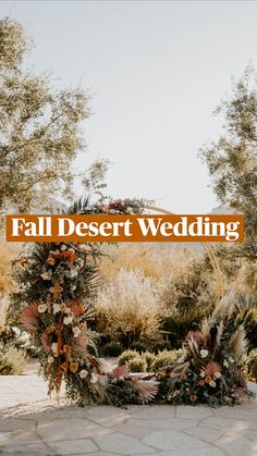 a wedding arch with flowers and greenery on the ground in front of some trees