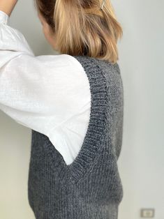 a woman with her hair pulled back in a pony tail style bun wearing a sweater vest