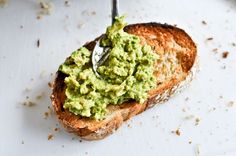 a piece of bread with guacamole on it and a spoon in the middle