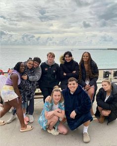 a group of people standing next to each other in front of a body of water