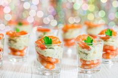 small cups filled with shrimp and garnish on top of a white tablecloth