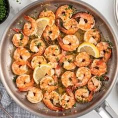 a pan filled with cooked shrimp and lemon wedges