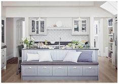 a kitchen with white cabinets and gray couch in front of an island counter top, surrounded by bookshelves