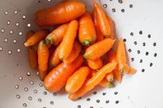 a white colander filled with lots of carrots