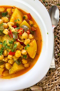 a white bowl filled with food on top of a woven place mat next to a spoon