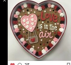 a heart shaped cookie with the words love is in the air