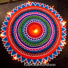 a lit candle in the middle of a colorful circular design