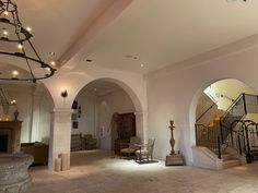 an empty living room with chandelier and stairs