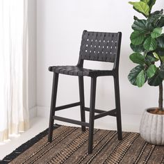 a chair next to a potted plant on a rug in front of a window