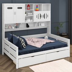 a white bed with two drawers and a blue blanket on top of it in a room