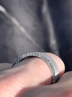 a person's hand holding a wedding ring with diamonds on the inside of it