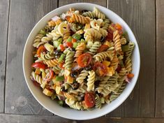 a white bowl filled with pasta salad on top of a wooden table