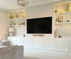 a large flat screen tv mounted to the side of a white wall in a living room