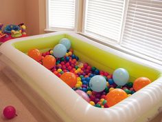 an inflatable pool with balls and toys on the floor next to a window