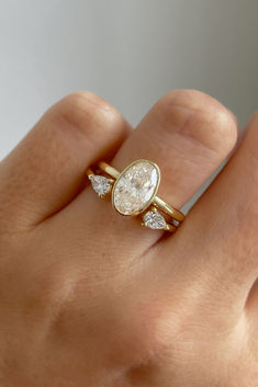 a woman's hand wearing a gold ring with three pear shaped diamonds on it