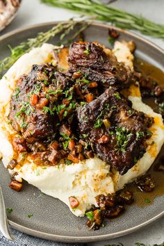 a plate with mashed potatoes topped with meat and garnish