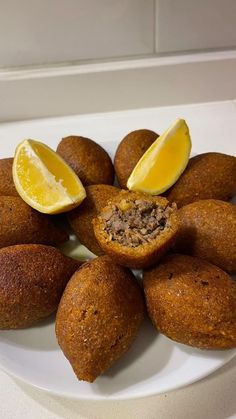 a white plate topped with muffins cut in half and lemon wedged into the middle