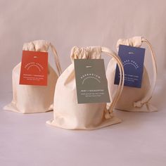 three bags with labels on them sitting side by side in front of a white background