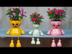 three colorful flower pots sitting on top of a blue shelf next to each other with flowers in them