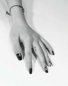 a woman's hand with black and white nail polish holding onto her bracelets