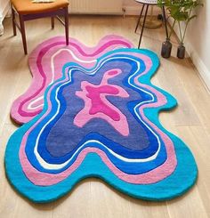 two rugs in the shape of an abstract flower on a wooden floor next to a chair and potted plant