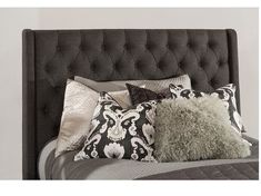 a bed with several pillows on it and a pillow in front of the headboard