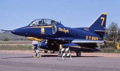 a blue fighter jet sitting on top of an airport tarmac next to another plane