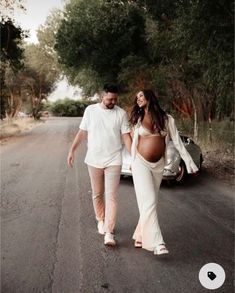 a pregnant woman walking down the road with her husband